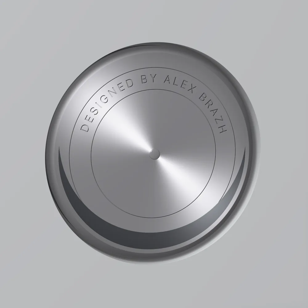 A close-up of the disk: brushed aluminium with a polished rivet at its centre, a dark steel crescent along its lower edge, and the words DESIGNED BY ALEX BRAZH engraved in spaced capitals round the top between two hairline circles